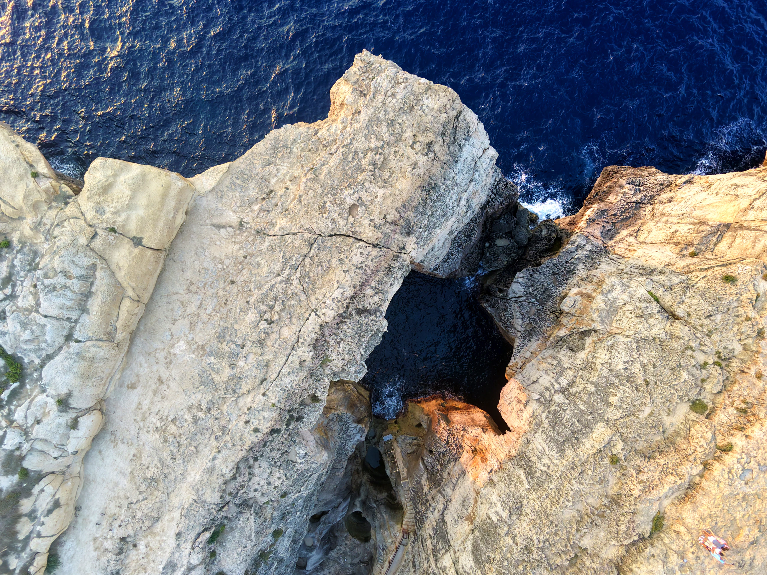 Limestone cliffs and the sea arch at Wied il-Mielaħ, Gozo, deep blue water below, seen from directly above